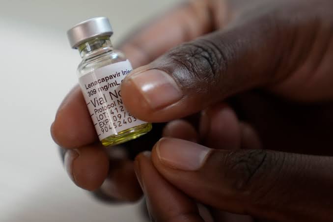 A vial of lenacapavir injection held in a pair of hands