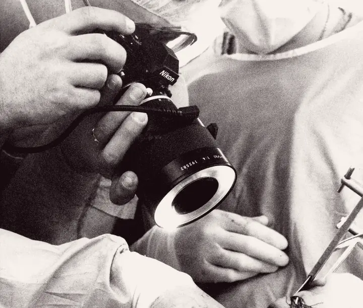 Hands holding a camera with a ring light beside a person in scrubs