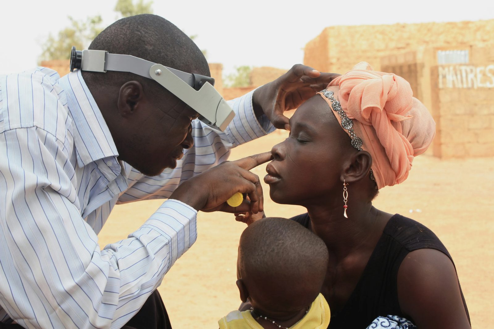 A health worker examining a woman's eye during a community outreach visit
