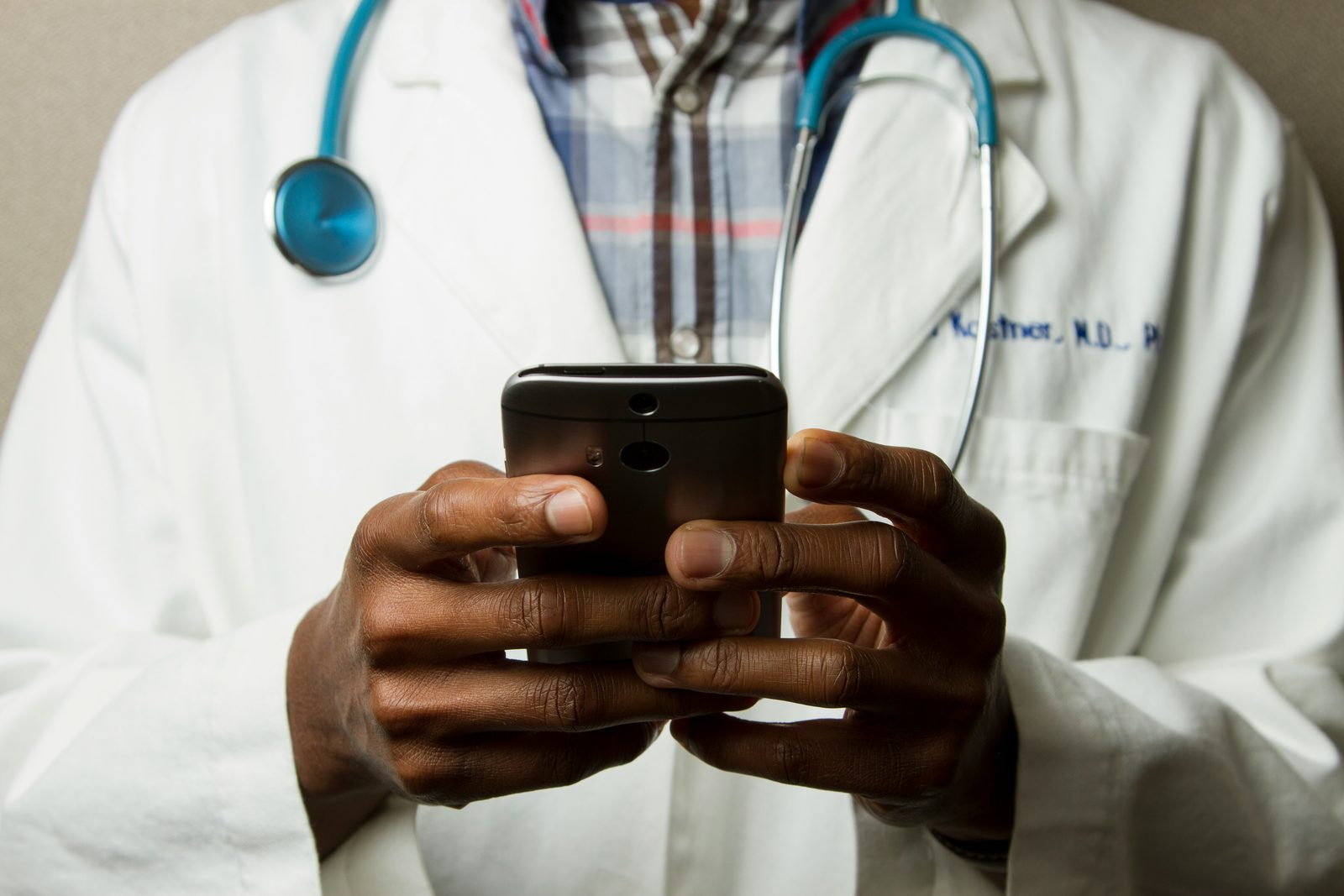 A doctor in a white coat reading on a mobile phone